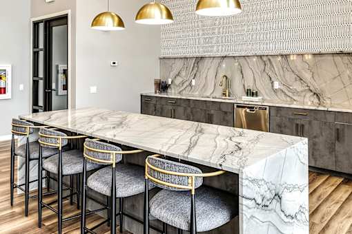 A kitchen with a marble countertop and bar stools.