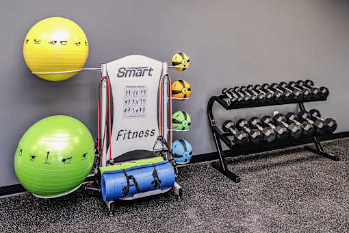 A Smart Fitness sign is displayed on a stand in a gym with exercise equipment.