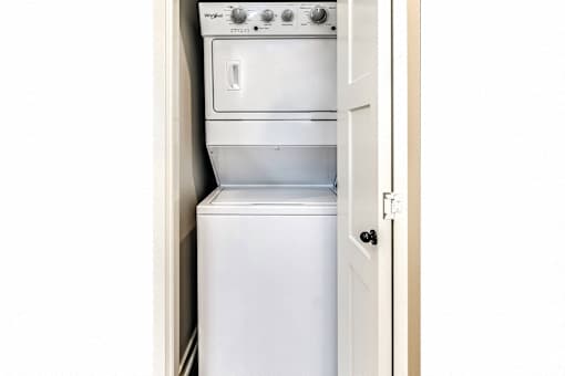 A white Washing machine and dryer stacked on top of each other.