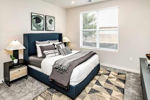 A bedroom with a large bed and two lamps.