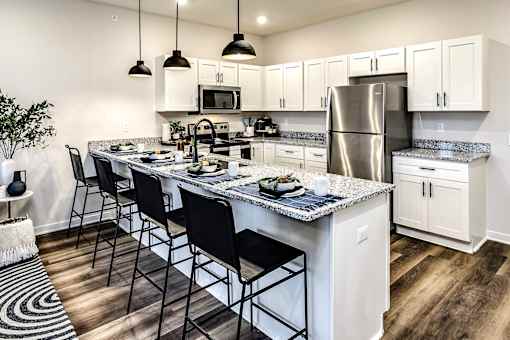 A kitchen with a white countertop and black chairs.