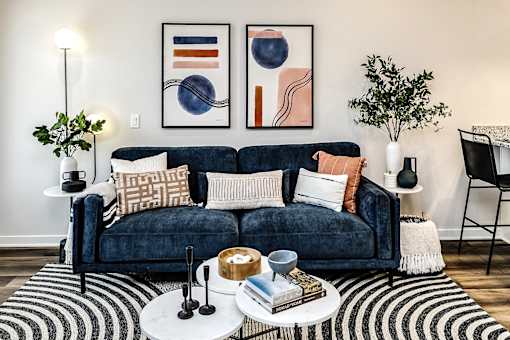 A living room with a blue couch and two framed artworks on the wall.