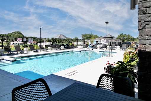 A pool with chairs and a sign that says "12:00" on it.