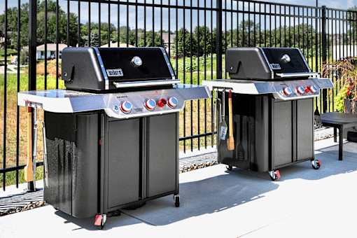 Two black barbecue grills with red knobs on them.