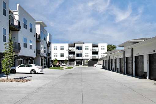 A white car is parked in a parking lot in front of a white building.