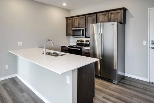 a kitchen with a white counter top and a stainless steel refrigerator