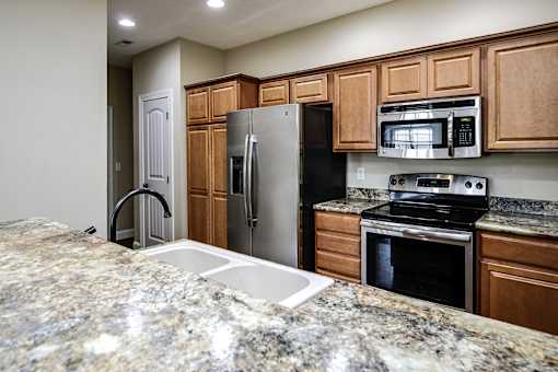 A kitchen with granite countertops and wooden cabinets.