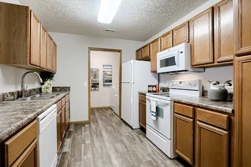 A kitchen with white appliances and wooden cabinets.