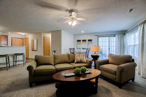 A living room with a brown sofa, a brown armchair, and a brown coffee table.