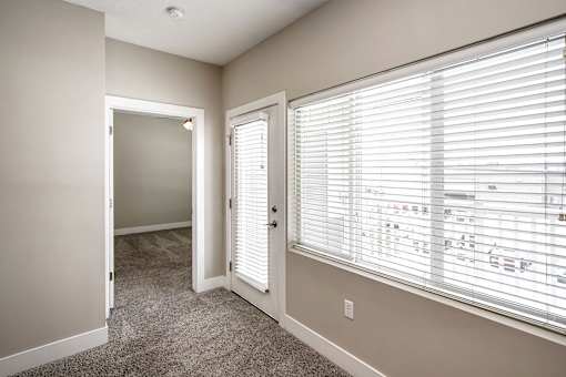 A room with a carpeted floor and a window with blinds.