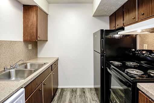 A kitchen with a black refrigerator and stove top oven.