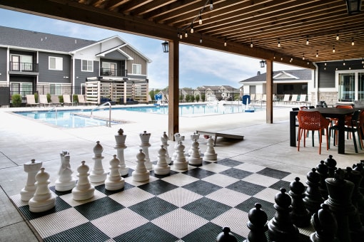 a large chess board in front of a swimming pool