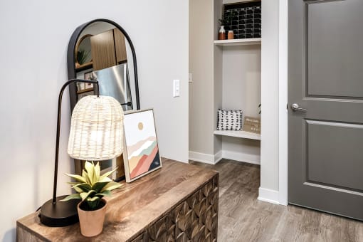 a living room with a mirror and a table with a plant and a dresser