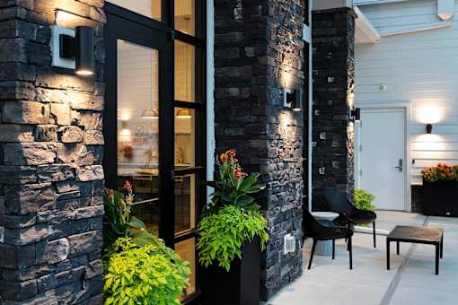 A black chair sits on a patio next to a stone wall.