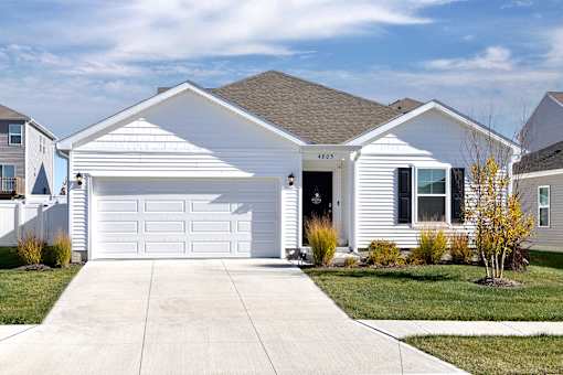 A white house with a garage door and a driveway in front.