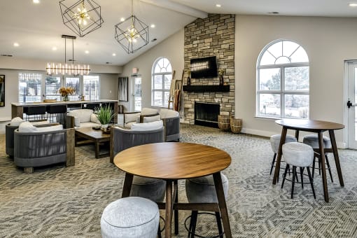 a resident clubhouse with couches tables and chairs and a fireplace at The Vue Apartments, Bellevue, NE