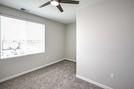 an empty room with a large window and a ceiling fan