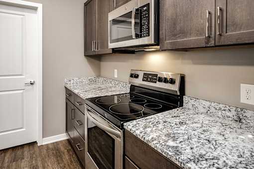 A kitchen with a granite countertop and stainless steel appliances.