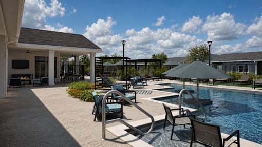 A poolside area with chairs and an umbrella.