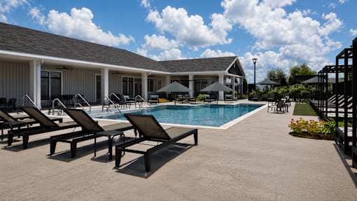 A poolside area with lounge chairs and a building in the background.