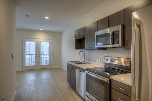 A kitchen with stainless steel appliances and wooden floors.