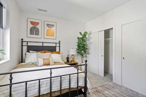 A bedroom with a black metal bed frame and a white bedspread.