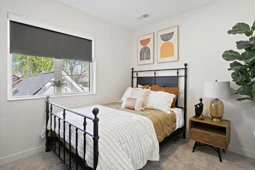 A bedroom with a large bed and a window with blinds.