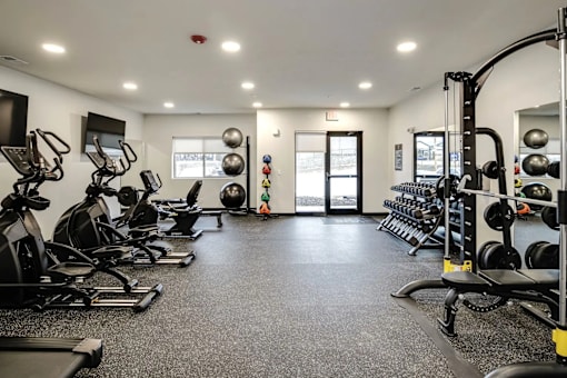 A spacious gym with a variety of equipment and a person in the background.