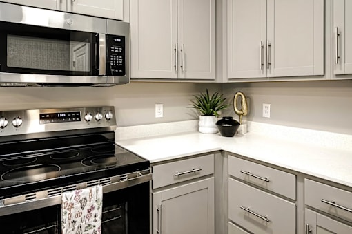 A modern kitchen with a black stove and white cabinets.