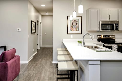 A kitchen with a red chair and a white counter.