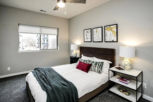 A bedroom with a bed, nightstand, and a window.