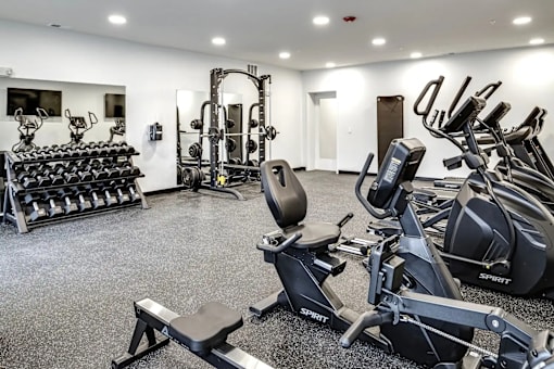 A gym with a variety of equipment including treadmills, weights, and exercise machines.