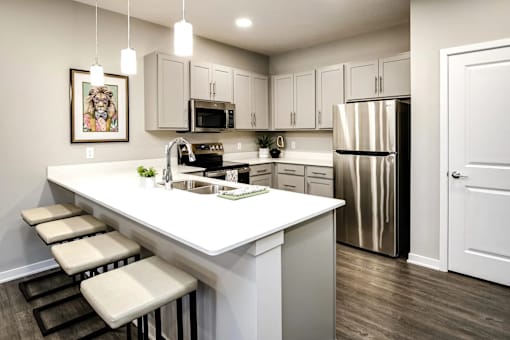 A kitchen with white countertops and stools.