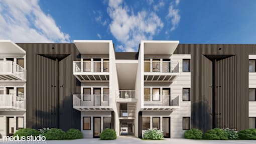 A modern apartment complex with balconies and a clear sky in the background.