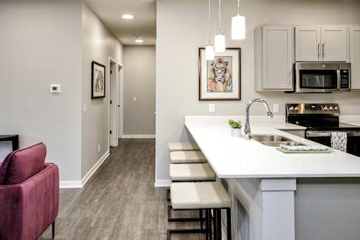 A kitchen with a red chair and a white counter.