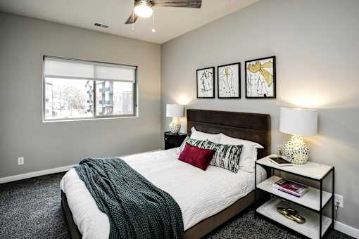 VUE 19 (Model 2Bd) - Bedroom with a bed, nightstand, and a window.