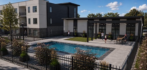 A black fence surrounds a small pool in a backyard.