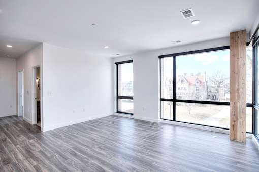 A large empty room with a wooden pillar and a view of the outside through the windows.