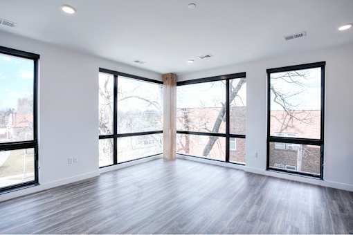 A spacious room with large windows and wooden flooring.