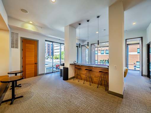 A room with a carpeted floor, a bar area, and a view of the outside.