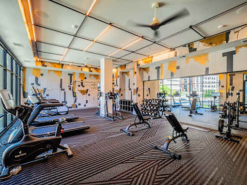 A gym with a variety of equipment including treadmills, stationary bikes, and weight machines.