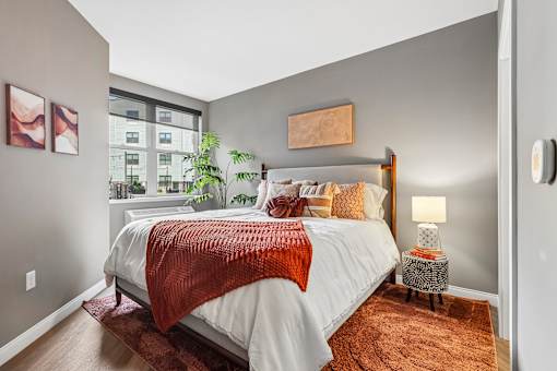 A bedroom with a large bed and a window overlooking a cityscape.