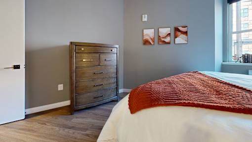A bedroom with a bed, dresser, and pictures on the wall.