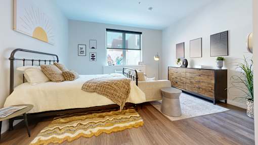 A bedroom with a bed, a chair, and a dresser.