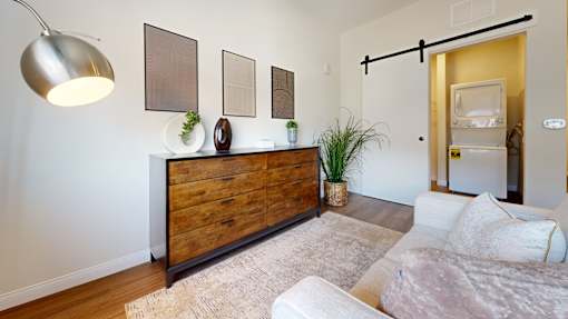 A modern living room with a wooden dresser and a white couch.