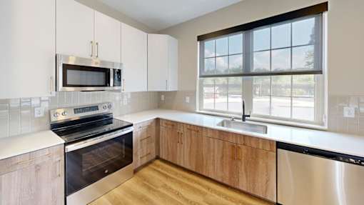 Kitchen with stainless appliances and large window at The Confluence Apartments, Pennsylvania