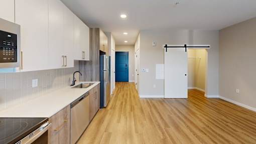 Galley kitchen and living area with barn door at The Confluence Apartments, Easton