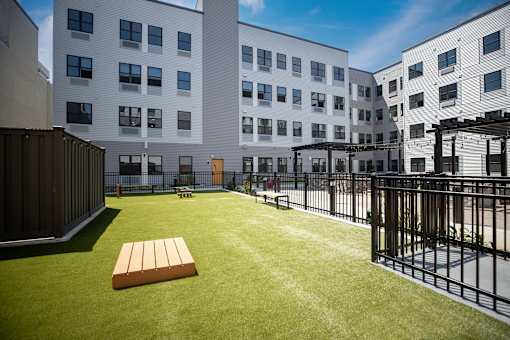 A grassy courtyard with a bench and a fence.