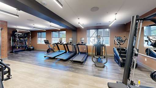 A gym with treadmills, elliptical machines, and other exercise equipment at The Standard Apartments, Pennsylvania