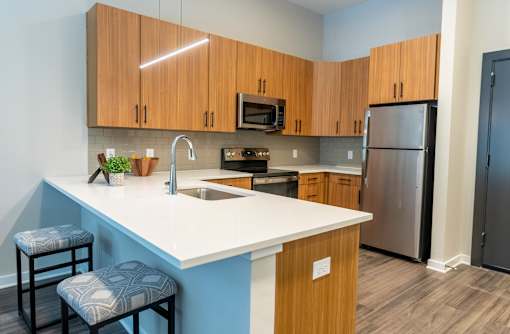 A kitchen with a white countertop and wooden cabinets at The Hive Apartments, Allentown, Pennsylvania